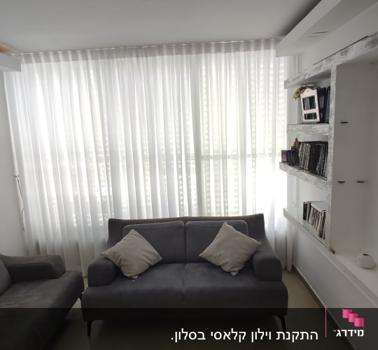 וילון לבן שקוף תלוי על חלון גדול בסלון